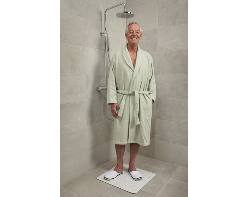 Man in badjas onder een regendouche op een douchemat
