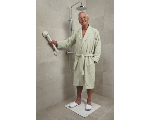 Man in badjas met douchekruk, handgreep en douchemat voor extra veiligheid