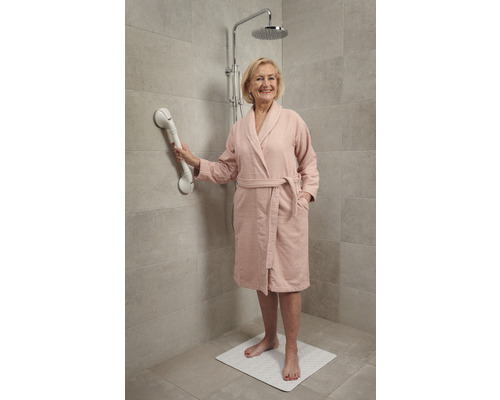 Vrouw in badjas gebruikt douchegreep op douchemat onder douchekop.