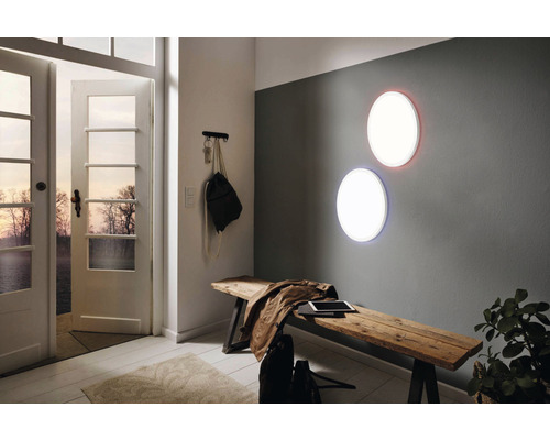 Hal met twee ronde wandlampen, houten bank en open deur