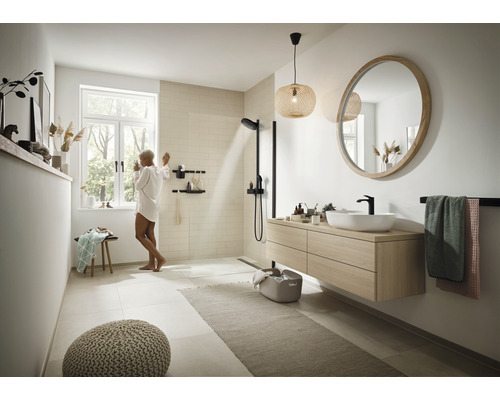 Lichte badkamer met douche, wastafel, spiegel en decoraties voor een moderne sfeer.