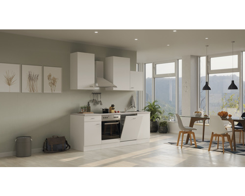 Moderne keuken met witte kasten, afzuigkap en eethoek in een lichte ruimte.