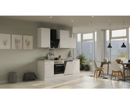 Lichte inbouwkeuken met witte kasten, afzuigkap en eethoek met tafel en stoelen.