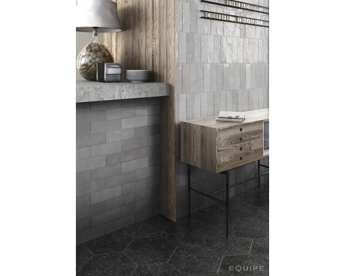 Interieur shot met grijze, rechthoekige wandtegels, plank en houten details.