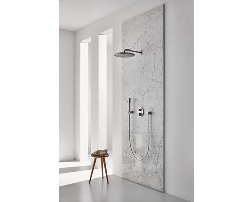 Doucheset met hoofddouche, handdouche en kraan op een marmeren wand in een lichte badkamer.