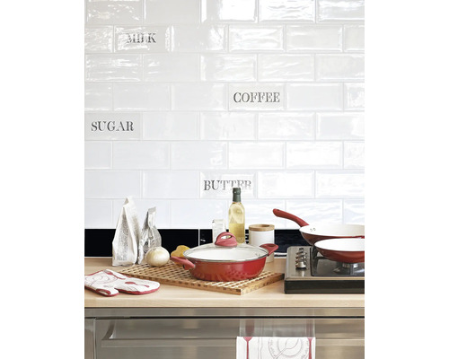 Keukenscène met kookgerei, voedingsmiddelen en witte metro tegels met opschriften