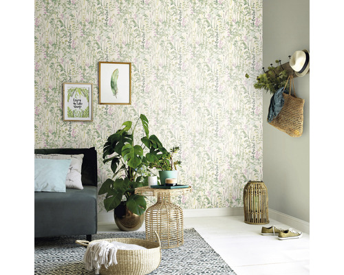 Woonkamer met bank, bijzettafel, kamerplanten, decoratie en behang met plantenmotief.