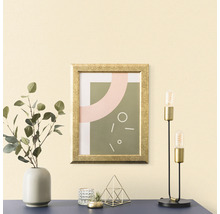 Decoratief arrangement met een ingelijste afbeelding, een vaas met eucalyptus, een theelichthouder, een decoratie en een tafellamp op een tafel