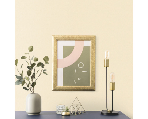 Decoratief arrangement met een ingelijste afbeelding, een vaas met eucalyptus, een theelichthouder, een decoratie en een tafellamp op een tafel