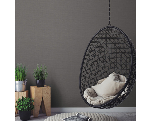 Woonkamer met rotan stoel, planten en grijs behang