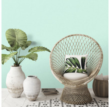 Decoratieve scène met een rotan stoel, planten in vazen en een vloerkleed met patroon