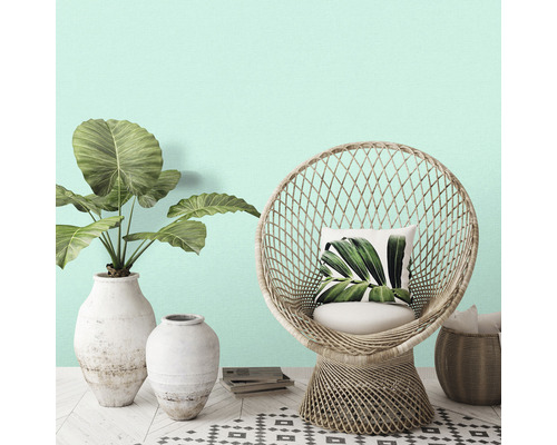 Decoratieve scène met een rotan stoel, planten in vazen en een vloerkleed met patroon