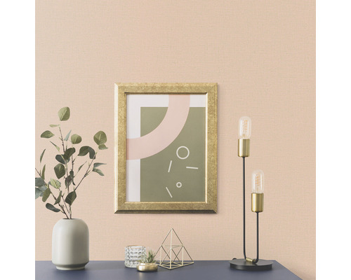 Woonkamer met een foto in een gouden lijst, een lamp en een vaas met planten op een dressoir.