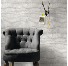 Grijze fauteuil voor een behang met golfpatroon, met een gewei erboven