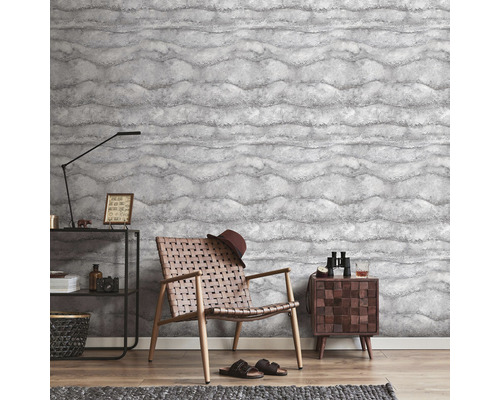 Woonkamer met patroonbehang, fauteuil en bijzettafel.