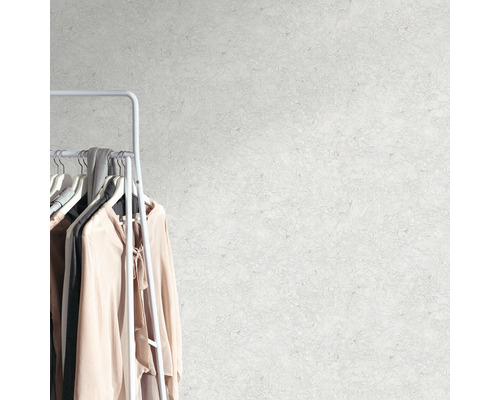 Muur met abstracte patronen naast een kledingrek met kledingstukken.