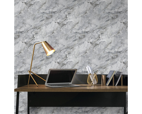 Bureau met lamp, laptop, pennenhouder en boeken voor een muur met marmerbehang