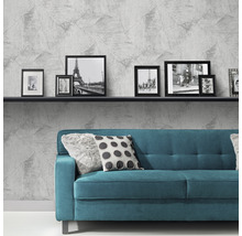 Woonkamer met grijs vliesbehang, bank en fotolijsten op een plank