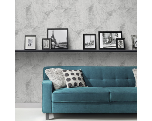 Woonkamer met grijs vliesbehang, bank en fotolijsten op een plank