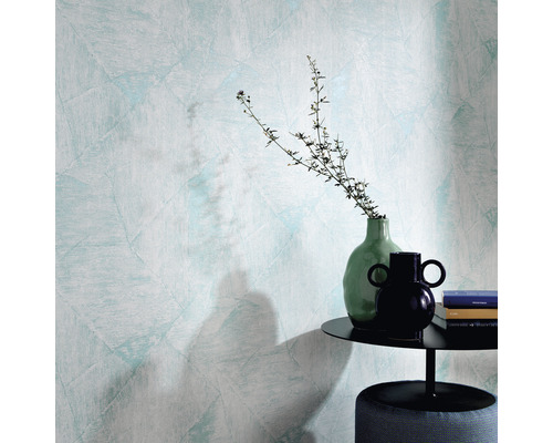 Close-up van een muur met structuurbehang, een bijzettafel met decoratie en een kruk.