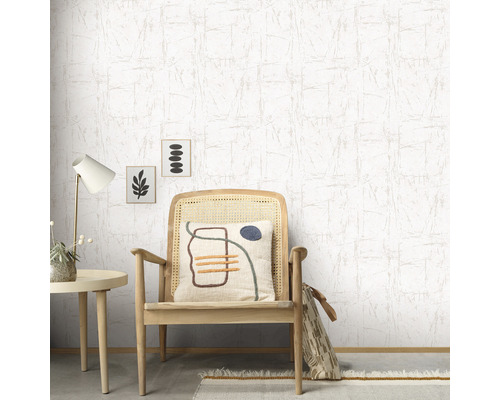 Scene met een gestructureerd behang, een houten stoel met kussen, een bijzettafel met lamp en decoratieve afbeeldingen.
