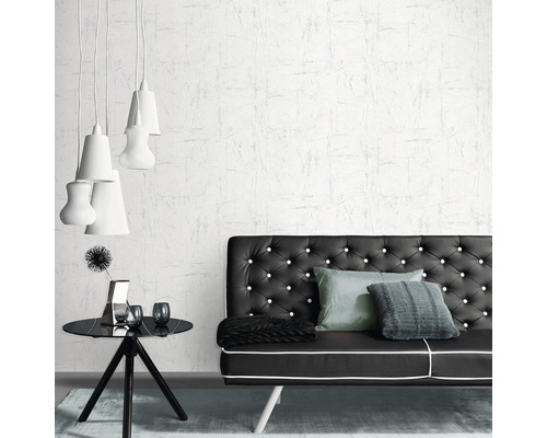 Een woonkamer met een zwarte bank, een zwart bijzettafeltje en wit behang.