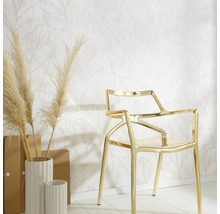 Decoratief behang met bladmotief, gecombineerd met gouden stoel en witte vazen op een lichte houten vloer.