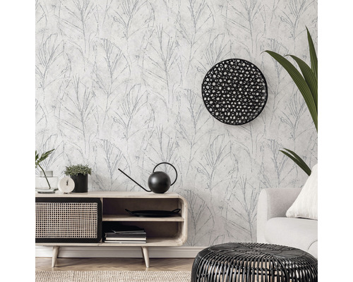 Woonkamer met patroonbehang, dressoir, fauteuil en decoraties.