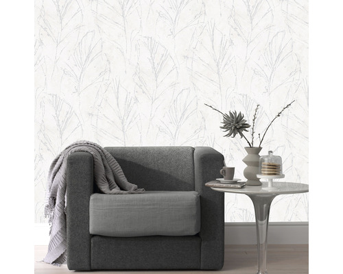 Woonkamer met fauteuil, tafel en behang met bladmotief