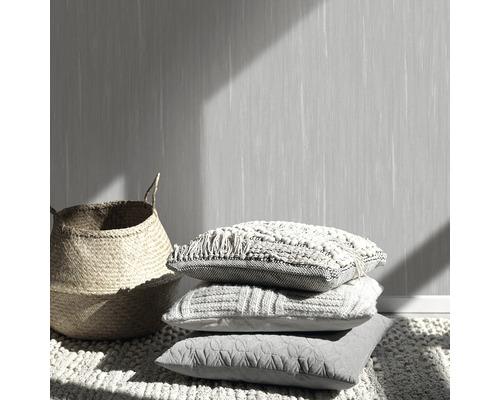 Decoratieve scène met stapel kussens, rieten mand en behang met patroon