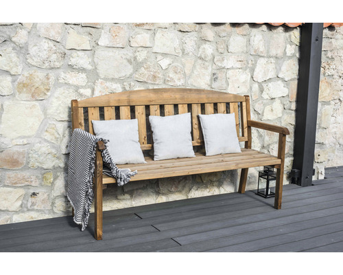 Houten bank met kussens en deken voor stenen muur
