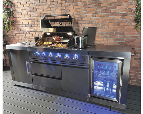 Roestvrijstalen buitenkeuken met barbecue, gootsteen en koelkast voor een bakstenen muur