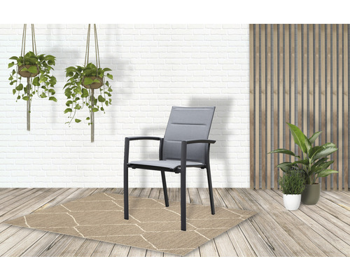 Tuinscène met een grijze tuinstoel op een vloerkleed met patroon