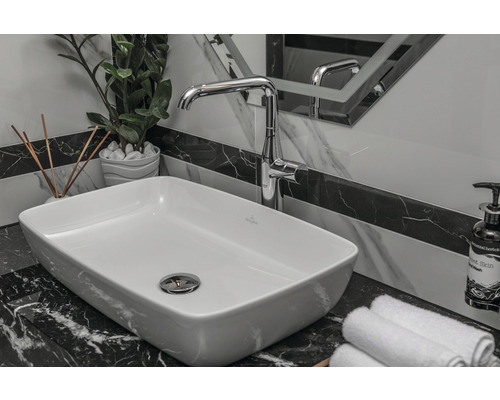 Badkamerwastafel met kraan, handdoeken en decoratie op een marmeren oppervlak