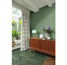 Woonkamer met groen textielbehang, tapijt, gordijnen en houten dressoir
