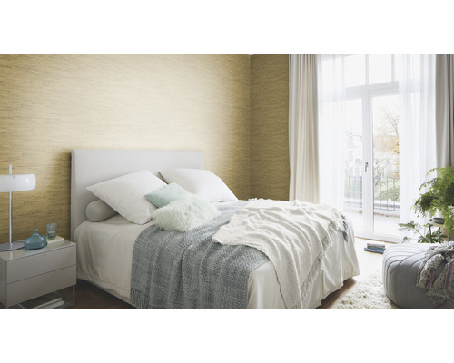 Slaapkamer met bed, nachtkastje en goudkleurig behang.