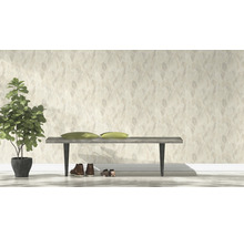 Lichte kamer met patroonbehang, bank, schoenen en kamerplant.