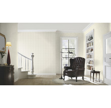 Woonkamer met fauteuil, staande lamp en trap met patroonbehang