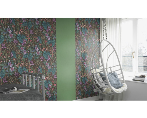 Gedecoreerde kamer met behang met bloemmotief, een schommelstoel en een bed.