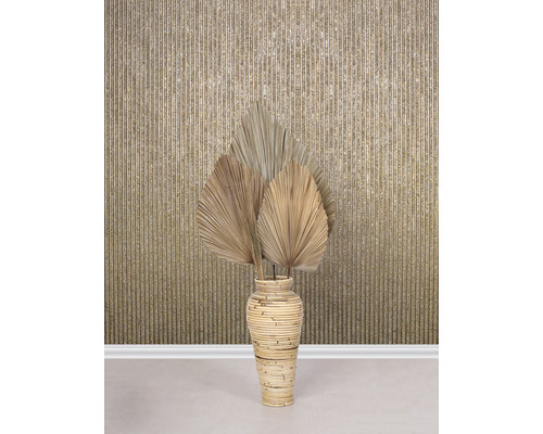 Decoratieve gedroogde palmbladeren in een bamboe vaas voor een wand met een gestreept patroon.