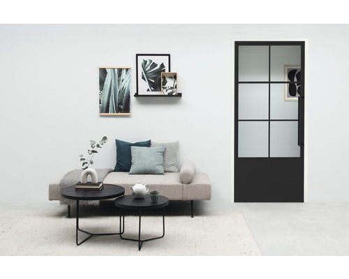 Woonkamer met daybed, salontafels en zwarte binnendeur met glazen paneel