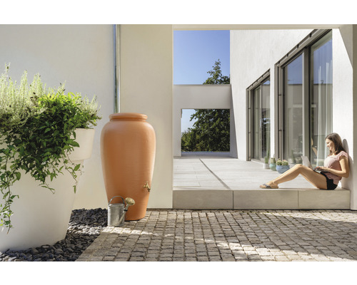 Scene met regenton, gieter en vrouw met laptop op het terras