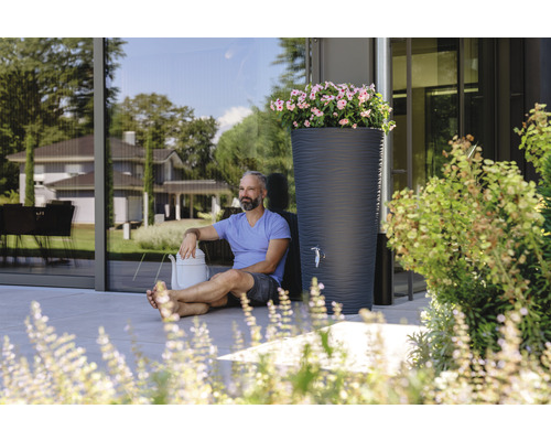 Scene met regenton, gieter en man in de tuin