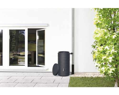 Regenton van kunststof naast de muur van het huis met regenpijp