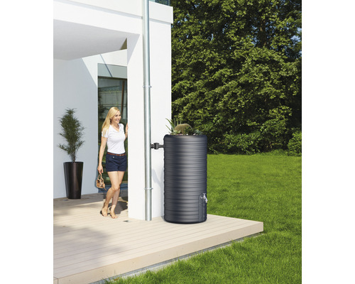 Regenton in de tuin naast een huis met een vrouw