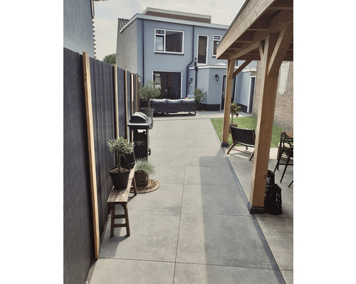 Buitenruimte met barbecue, tuinmeubelen en plantenbakken op een betegeld terras