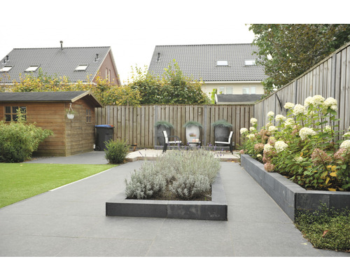 Aangelegde tuin met bestrating, plantenbakken en houten schutting