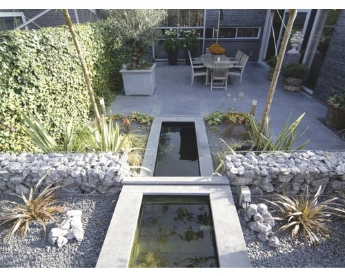 Tuinscene met steenkorven, waterspel en zithoek
