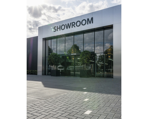 Entree van een showroom met glazen gevel en plantenbakken
