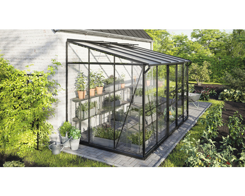 Glazen en metalen kas met plantenplanken in de tuin.